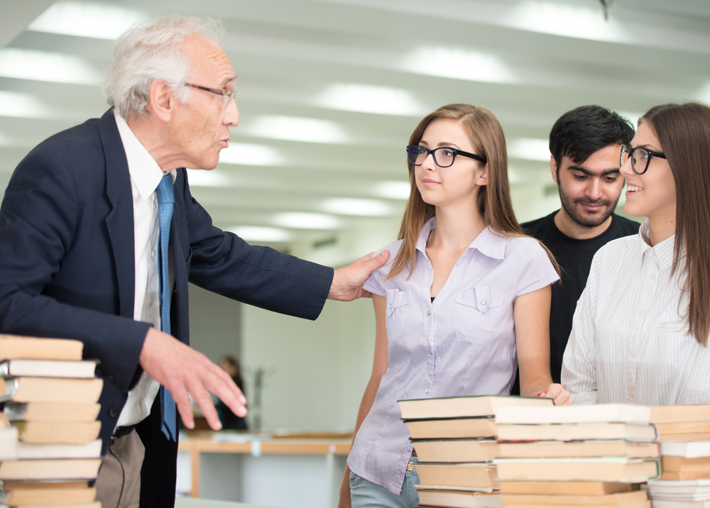 Senior professor giving lecture to young students at college campus